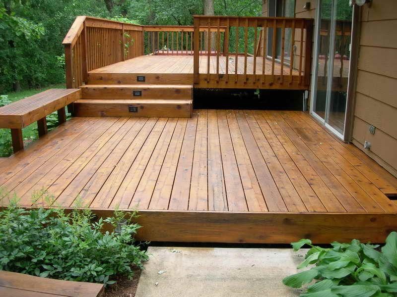 Cedar deck with a built-in bench and steps in a wooded backyard