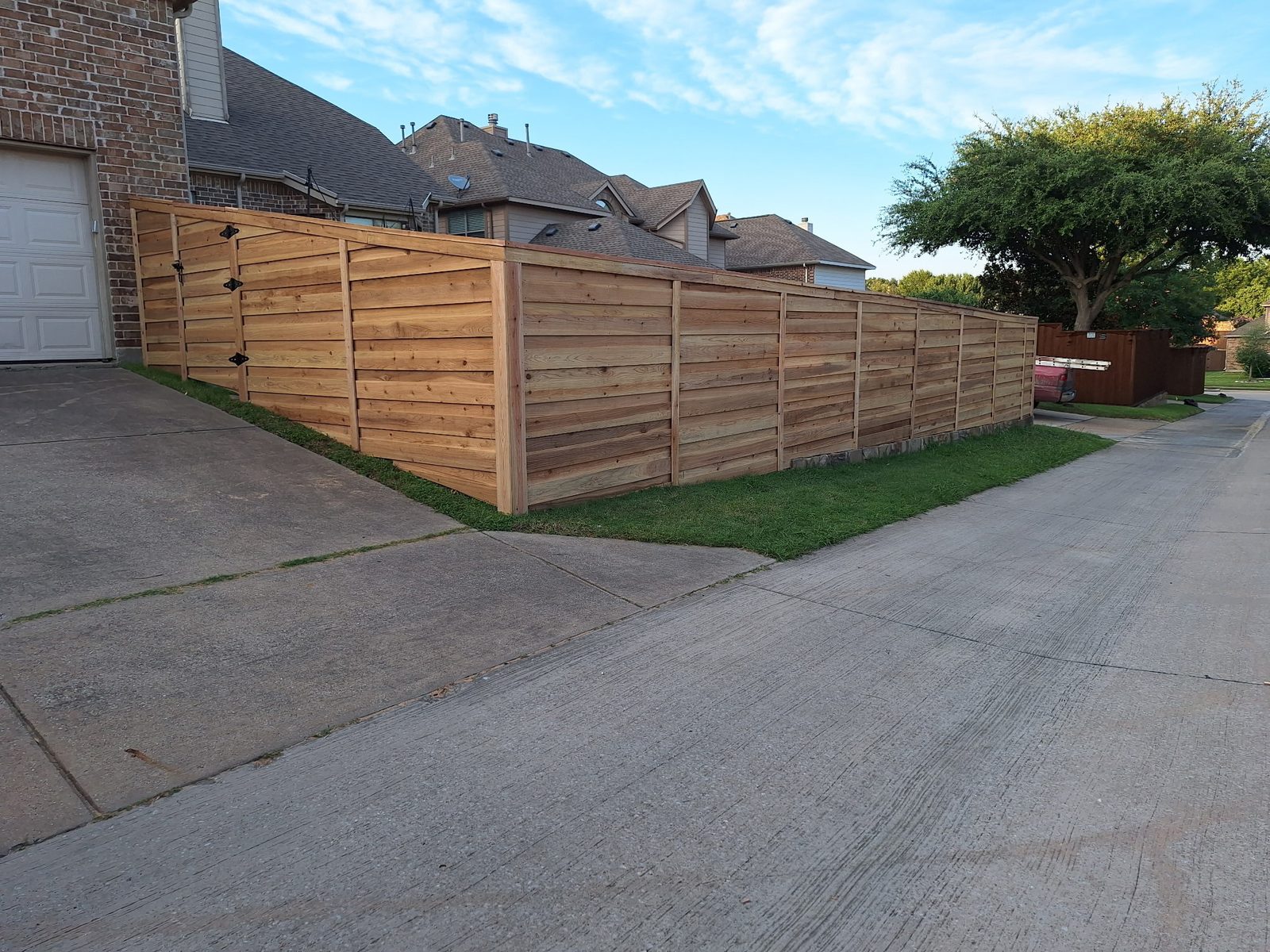 Horizontal cedar privacy fence with matching gate along a driveway