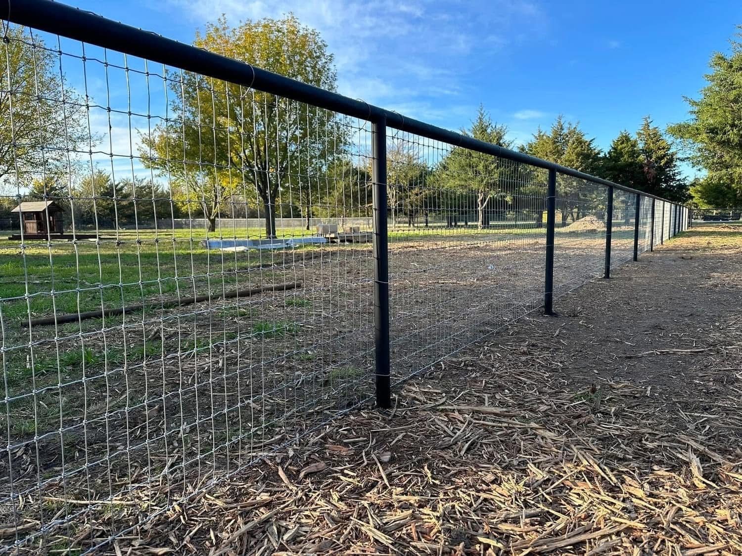 Black pipe-top wire field fence enclosing an open pasture