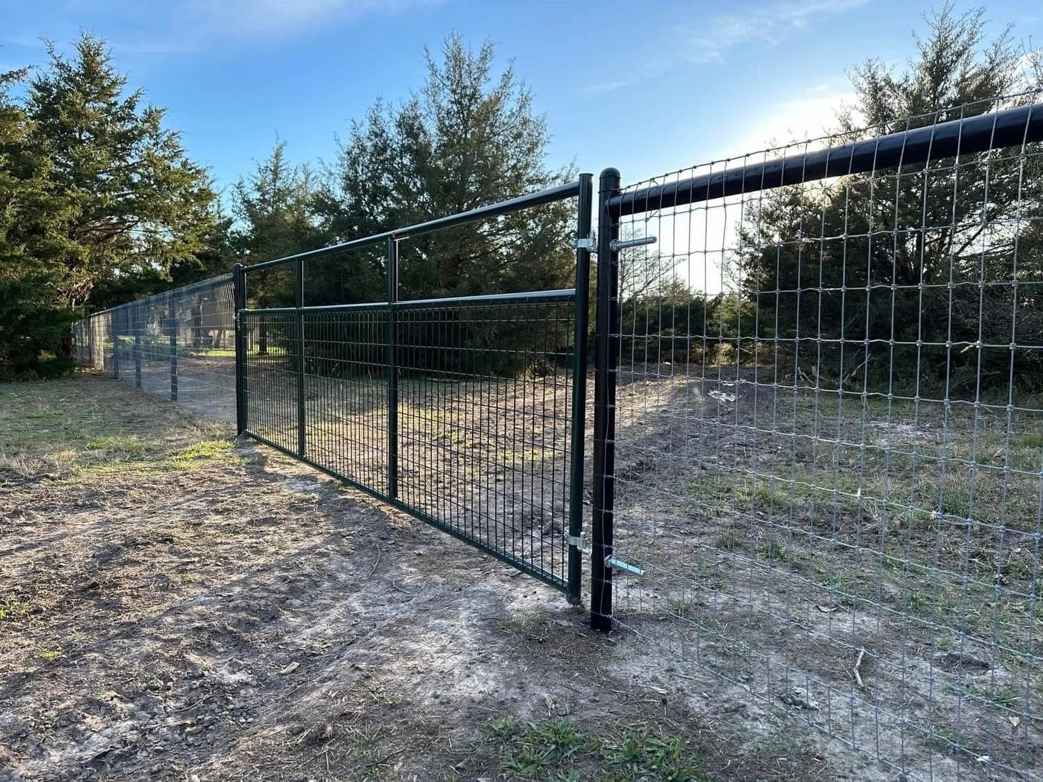 Black welded-wire ranch fence with a matching swing gate on a rural lot